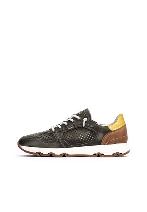 Zapatilla deportiva con parte superior de cuero verde oscuro con perforaciones, cordones grises y detalles en marrón y amarillo. Media suela blanca con suela texturizada.