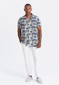 Chemise à manches courtes avec un col, ornée d'un motif floral bleu, assortie à un pantalon blanc et des chaussures à enfiler grises. Tissu lisse, coupe décontractée.
