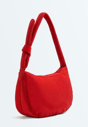 Sac épaule en tissu rouge doux avec une large bandoulière rembourrée et un détail de nœud sur un fond clair uni.