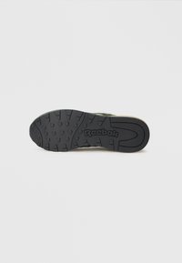 Melna gumijas zole ar teksturētu virsmu, kurā ir redzams "Reebok" logotips. Izstrādāta saķerei ar izvirzītiem rakstiem un rieviņām.