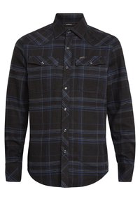Camisa de franela ajustada en negro con un patrón de cuadros azules y grises. Cuenta con dos bolsillos en el pecho, cierres de botón y un cuello puntiagudo. Textura suave.