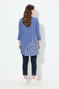 Tunika blu con orlo a paisley, scollatura rotonda e maniche a tre quarti, abbinata a leggings navy con pizzo.