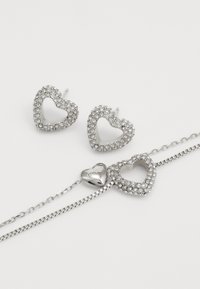 Silberne herzförmige Ohrringe und ein Armband, verziert mit klaren Strasssteinen und einem eingravierten Herzanhänger, mit einem glatten Kettendesign.