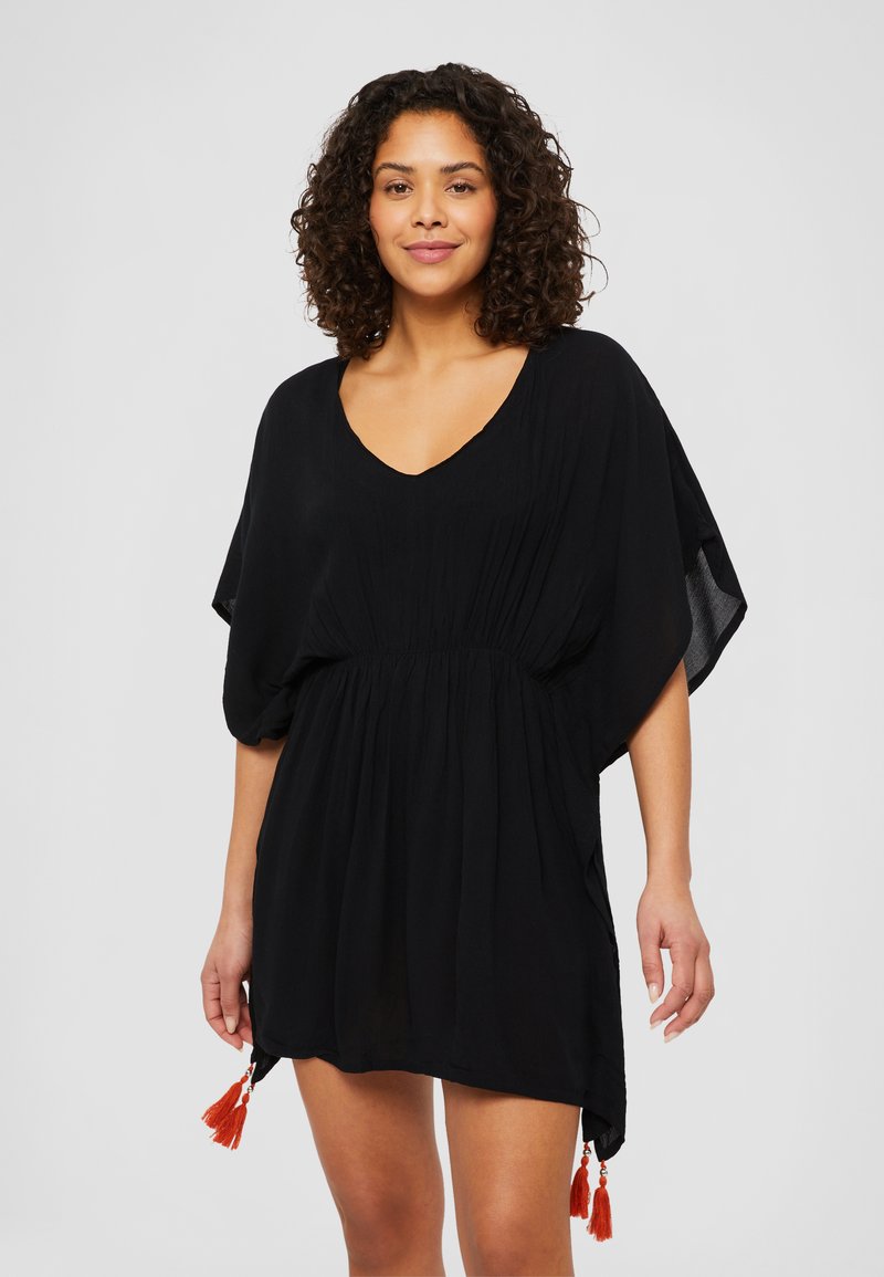 Black kaftan dress with a V-neck, short sleeves, gathered waist, and two orange tassel accents at the hem. Smooth, lightweight fabric.