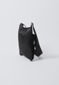 Borsa a spalla nera in nylon con una superficie liscia, chiusura con zip e una tracolla regolabile. Presenta una forma semplice e rettangolare e un design minimalista.