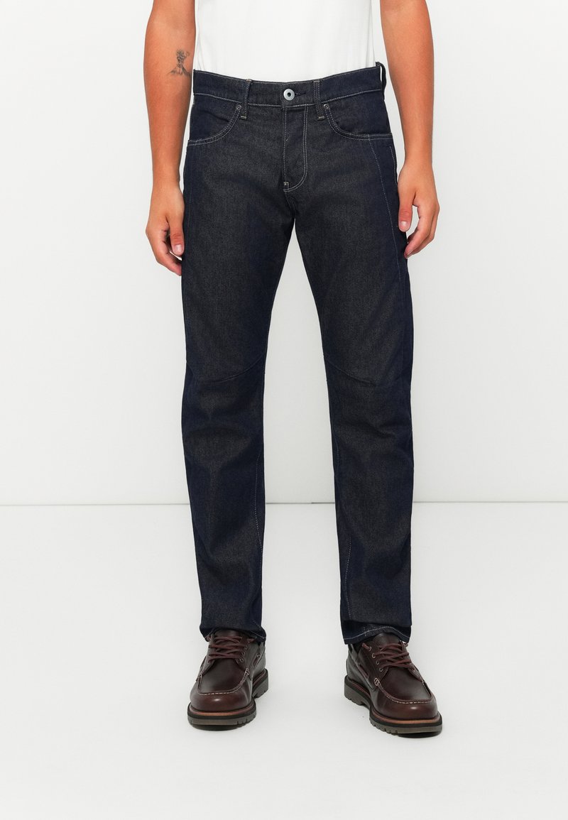 Dunkelblaue Jeans im geraden Schnitt, mit fünf Taschen und weißen Nähten. Ausgestattet mit einem Knopfverschluss und Gürtelschlaufen.