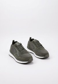 Chaussures de sport vertes en mesh et en suede, avec un système de laçage, des accents gris et une semelle intermédiaire blanche avec une semelle extérieure texturée.