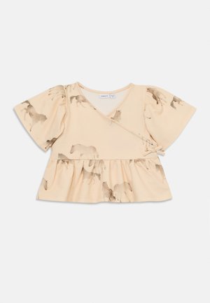 Top creme pálido com mangas curtas bufantes, design envolvente e cintura peplum. Apresenta um padrão de cavalos em aquarela em tons suaves de castanho.