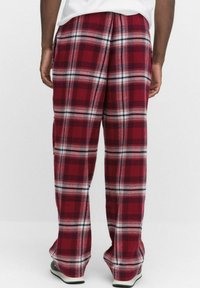 Rood-witte geruite pyjamabroek met een relaxed fit, voorzien van een trekkoord in de taille en zijzakken. Zacht, gestructureerd materiaal over de hele broek.