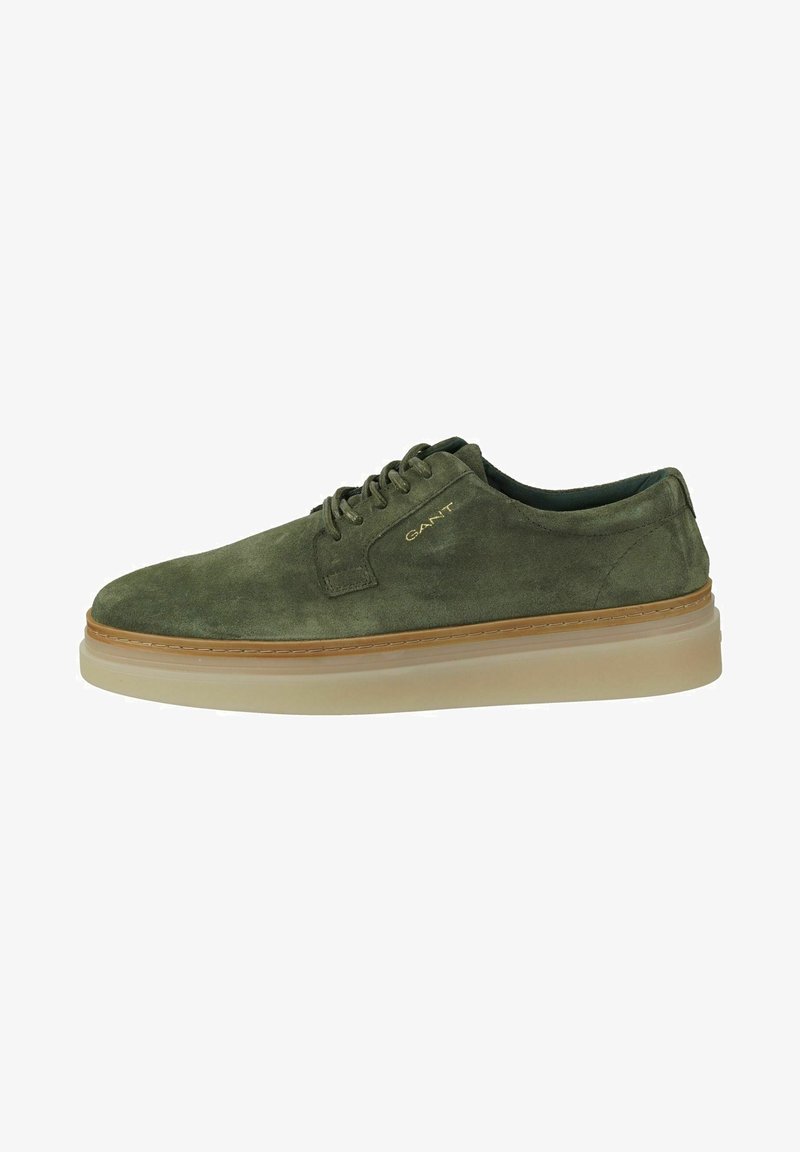 Chaussure en daim vert à bout arrondi, avec un design à lacets et une semelle légère et amortie. Présente un logo discret sur le côté et un bord contrastant couleur tan.