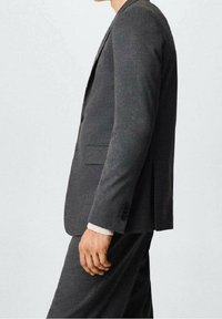 Blazer gris foncé à la coupe structurée, avec un bouton unique à l'avant, des revers à crans et une texture subtile. Comprend des fentes latérales et à l'arrière.