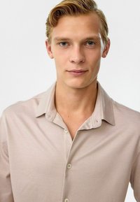 Korte mouwen, licht beige shirt met een knoopsluiting en een klassieke kraag. De stof lijkt glad te zijn met een subtiele glans.