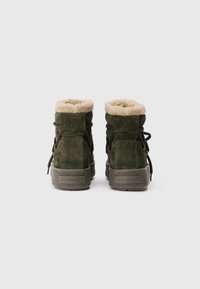 Stivaletti alla caviglia in suede verde con fodera in pelliccia, chiusura con lacci e suole in gomma testurizzata. Presenta il marchio impresso sul tallone.