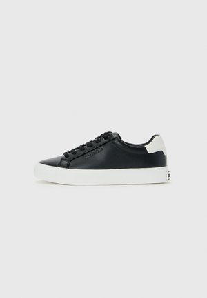 Sneaker nera a basso profilo con suola e tallone bianchi, lacci neri e sottile logo Calvin Klein di lato, esposta su uno sfondo neutro.