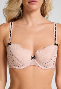 Roze kant en polka dot beha met onderdraad, met zwarte accenten, delicate strikdetails en verstelbare bandjes. Getextureerd kant op de cups.
