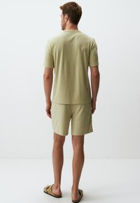 Jasnozielony zestaw z bawełnianą koszulką i szortami. Koszulka ma krótkie rękawy i okrągły dekolt. Szorty są do kolan i mają luźny krój.