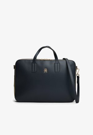Marineblaue Ledertasche mit zwei Obergriffen und einem verstellbaren Tragegurt. Verfügt über goldene Hardware und ein auffälliges Logo auf der Vorderseite. Glatte Textur.