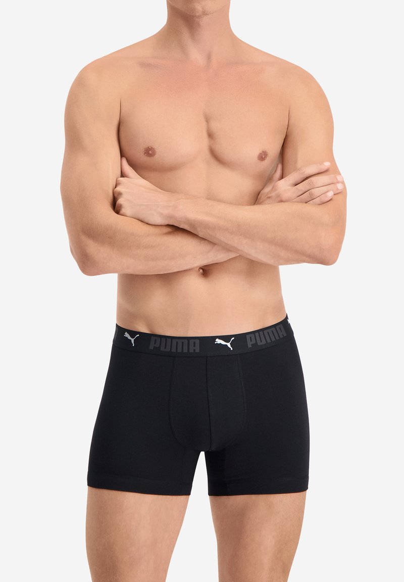 Schwarze Boxershorts aus Baumwollmix, mit einem grauen elastischen Bund, der den Markennamen und das Logo trägt. Eng anliegendes Design mit glatter Textur.