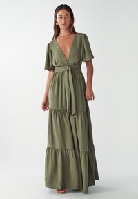 Olivgrünes Maxikleid mit tiefem V-Ausschnitt, kurzen Puffärmeln, Knopfleiste, gebundenem Taillengürtel und gestuftem Rock. Weicher, strukturierter Stoff.