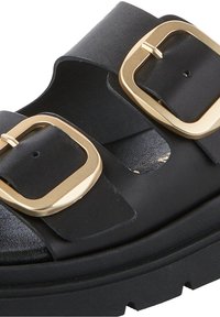 Zwarte leren sandaal met twee brede banden en goudkleurige vierkante gespen. Heeft een chunky zool en een gladde textuur.