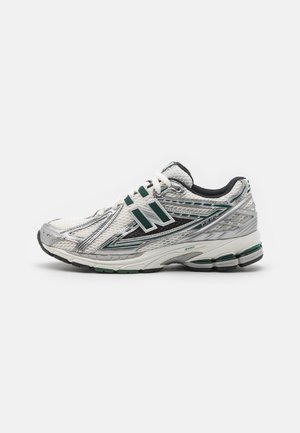 Zapatilla de running para hombre con parte superior de malla en plata, blanco y verde. Cuenta con una suela acolchada, cordones y un logotipo en el lateral. Suela de goma.