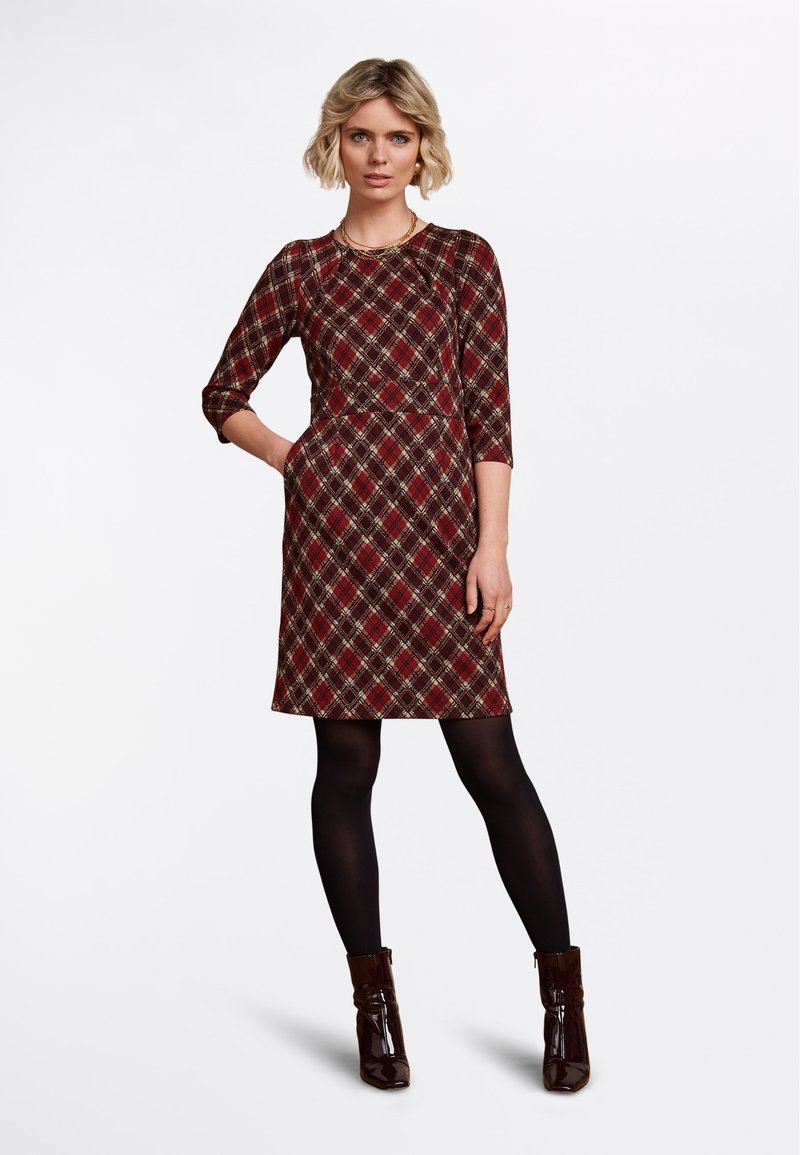 Rotes karierter Kleid mit Dreiviertelärmeln, Rundhalsausschnitt und definiertem Bund. Kombiniert mit schwarzen Strumpfhosen und glänzenden braunen Ankle Boots.
