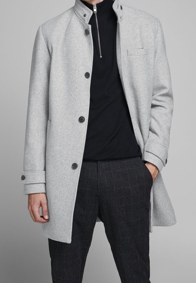 Abrigo de lana gris claro con cuello alto, cierres de botón, un bolsillo en el pecho y una textura suave, combinado con pantalones oscuros de cuadros.