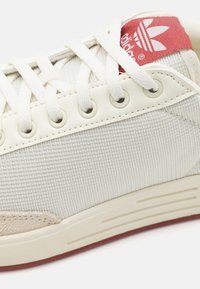 Ljusgrön sneaker med texturerad kanvasöverdel, beige mockadetaljer och röd logotag. Har rund snörning och perforerade sidodetaljer.