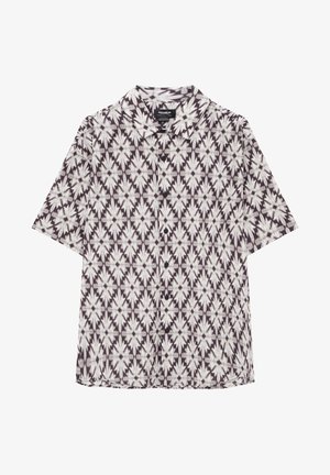 Camisa de manga corta con patrón en blanco y negro y botones, superpuesta a un crop top blanco con gráfico rosa, combinada con una minifalda rosa.