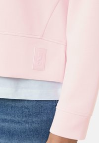 Lichtroze sweatshirt met een cropped ontwerp, een soepele textuur en een gestikte zoom met een subtiele logo-opdruk aan de onderkant.