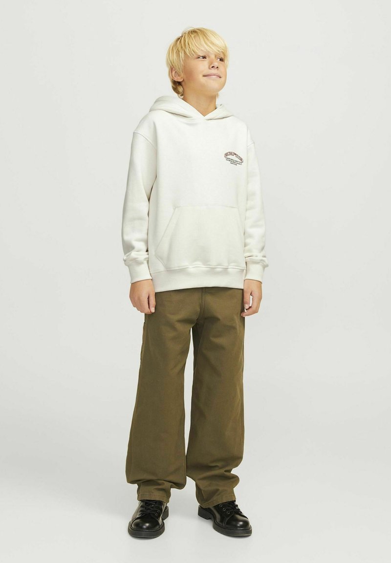 Cream hoodie with a front pocket and brown embroidered logo, paired with loose olive green pants and black shoes. Smooth fabric texture.