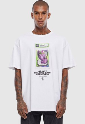 Hvit oversized t-skjorte med et fargerikt grafisk design av en lilla karakter, rammet inn i et kunstnerhandelskort-design med svart tekst under.