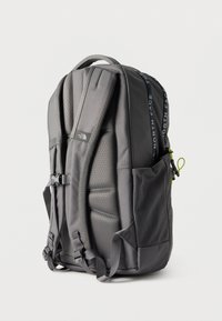 Γκρι σακίδιο North Face με επενδεδυμένους ιμάντες ώμου, δίχτυ στην πλαϊνή τσέπη, λαβή στο επάνω μέρος και φερμουάρ με λογότυπο, εμφανίζεται από την πίσω πλευρά.