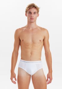 Hvide trusser med en blød elastik, der er mærket "JBS UNDERWEAR," med et glat, tætsiddende design og minimalistisk stil.