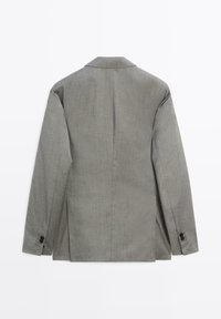 Grauer Blazer mit einer strukturierten Gestaltung, einem einzelnen Schlitz am Rücken und zwei Knopfverzierungen am Ärmelabschluss. Hergestellt aus strukturiertem Stoff.