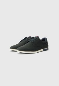 Dark green suede shoes with beige rubber soles, flat laces, and small blue and red accent on the heel. Classic design suitable for casual wear.