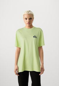 Light green t-shirt with a relaxed fit, made of cotton, featuring a small navy logo on the left chest, round neckline, and short sleeves.