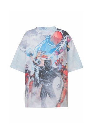 To personer iført oversized Marvel superhelte T-shirts og lyseblå joggingbukser står mod en ensfarvet lys baggrund.