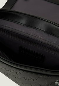 Interno di una borsa in pelle nera che presenta una texture liscia, una fodera in tessuto scuro e una tasca con zip dotata di un'etichetta del marchio.