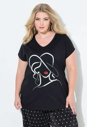 T-shirt nera a scollo a V con una linea bianca che disegna il volto di una donna con labbra rosse e un cappello. Materiale in cotone morbido, vestibilità rilassata.