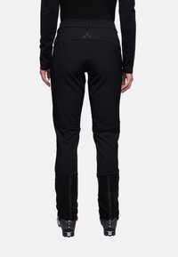 Zwarte skibroek met een aansluitend ontwerp, rekbaar materiaal, verstevigde kniestukken en ritsen bij de enkels, geschikt voor wintersport.