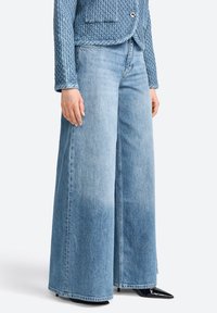 Heledad sinine laiad denim püksid, millel on tuhm efekt, kõrge vöökoht ja sirge siluett. Alusosa on puhtalt viimistletud.