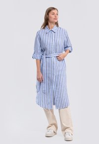 Light blue and white striped button-up dress with roll-up sleeves, a tied waist, and a knee-length cut, made from a textured fabric.
