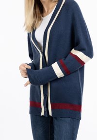 Marinblå cardigan med krämfärgade och vinröda ränder, knäppning med knappar, ribbade ärmslut och nederkant, tillverkad av mjukt strukturerat stickat tyg.