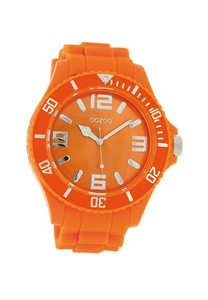 Montre en silicone orange avec un cadran rond, des repères numériques blancs et des aiguilles argentées. Elle possède des repères horaires audacieux et une lunette texturée.
