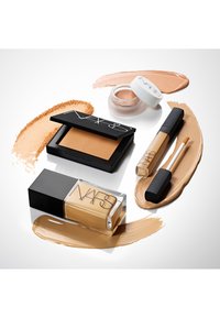 Collezione trucco NARS che include una bottiglia di fondotinta liquido trasparente, cipria compatta, crema e correttore in diverse tonalità e texture di tan.
