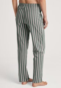 Gestreepte pyjamabroek in donkergroen met roze en witte verticale strepen. Zacht fabric, elastische tailleband, rechte pasvorm en enkellang.