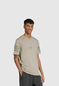Hellgraues Baumwoll-T-Shirt mit grünen Streifenakzenten an den Ärmeln und einem kleinen Logo auf der Brust. Kurze Ärmel, normale Passform.