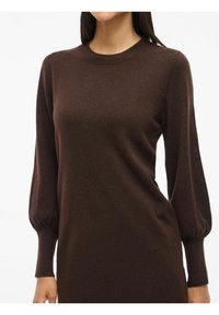 Pull marron à col rond, avec de longues manches bouffantes, des poignets côtelés et un tricot doux et texturé.