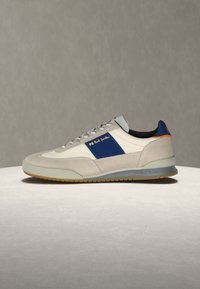 Μπεζ και λευκό αθλητικό παπούτσι με μπλε πλαϊνή επιφάνεια, γκρίζα σόλα και κορδόνια, με το σήμα "PS Paul Smith" σε κίτρινο στο πλάι.